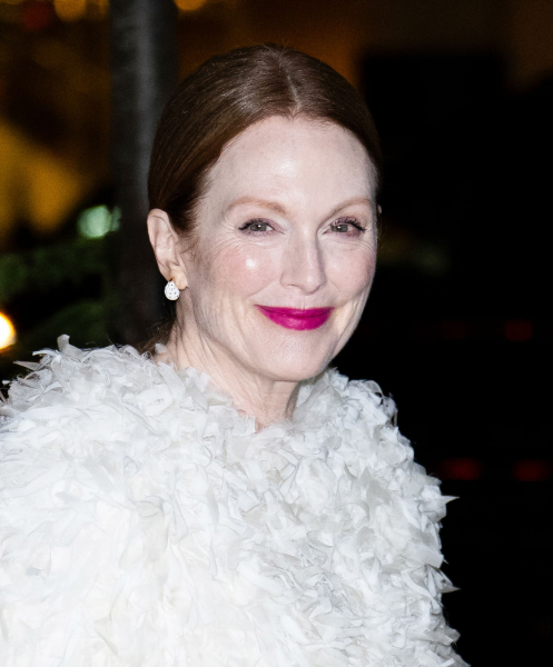 Julianne Moore smiles in a ruffled white jacket and bright pink lip.